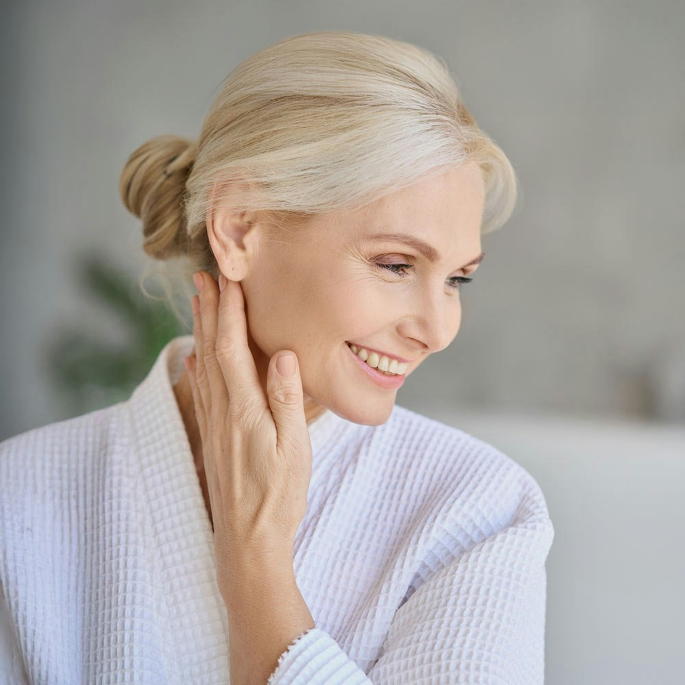 middle-aged woman smiling while touching her jawline