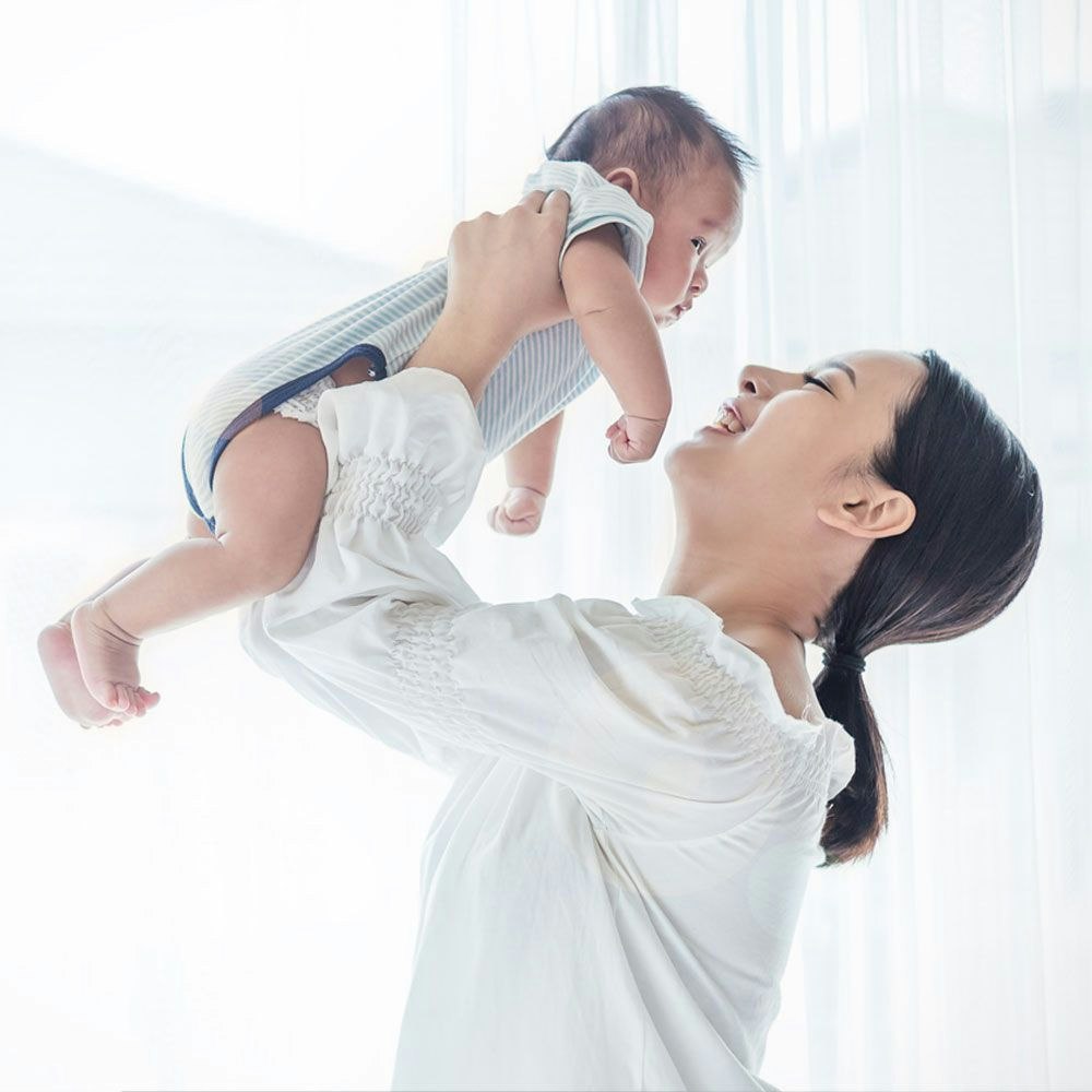 Smiling mother lifting up baby