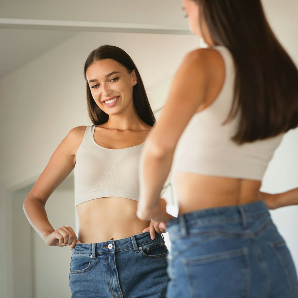 Slim smiling woman in large jeans after bariatric surgery