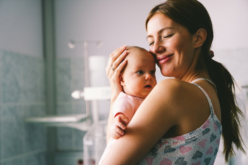 Smiling mother after mommy makeover holding baby