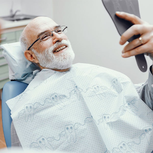 smiling man looking in the mirror after cosmetic dentistry