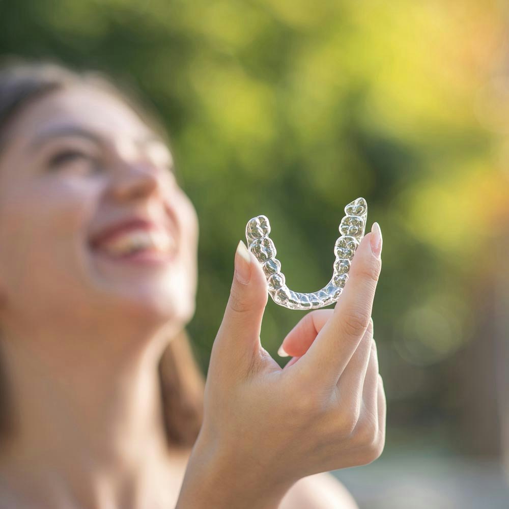 Laughing woman holding Invisalign aligner