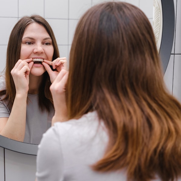 Woman placing Invisalign in front of mirror