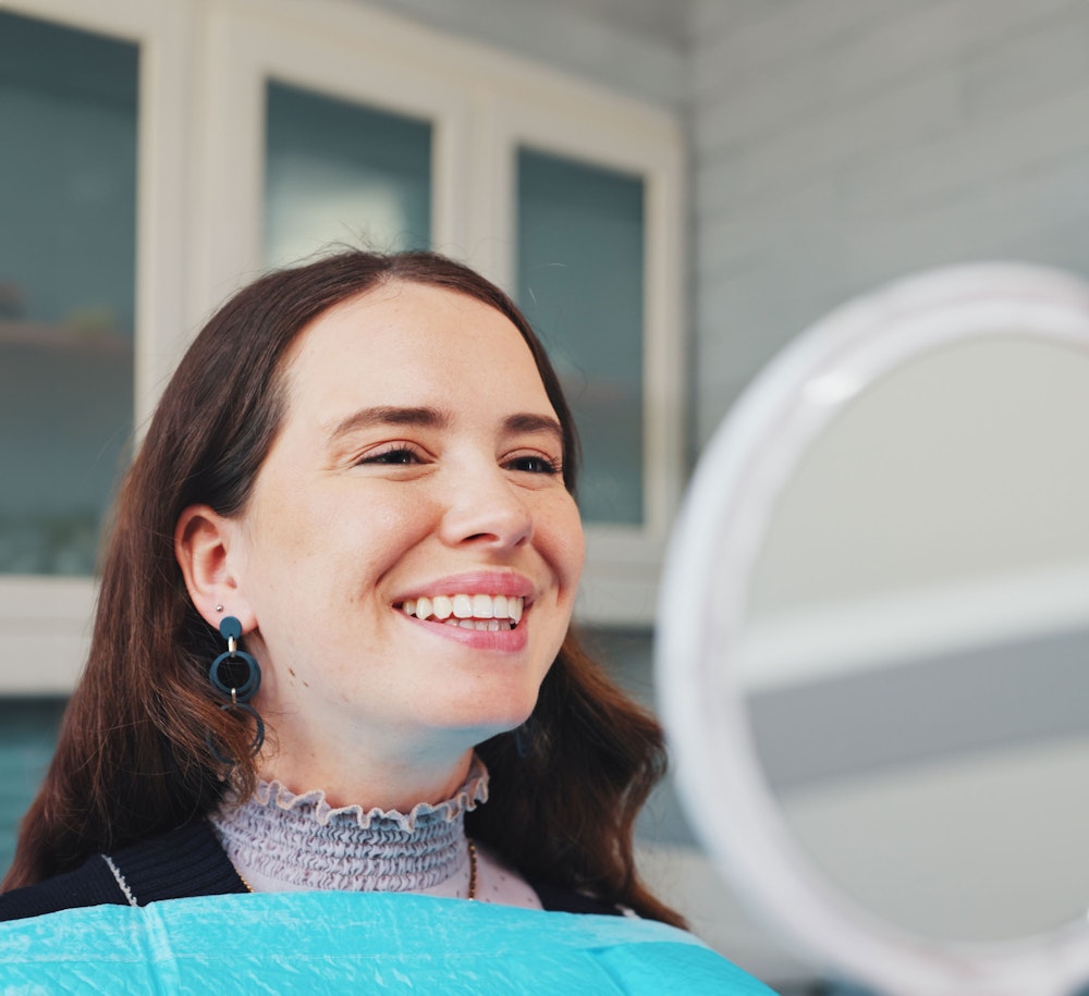 Woman smiling in a mirror at the dentist