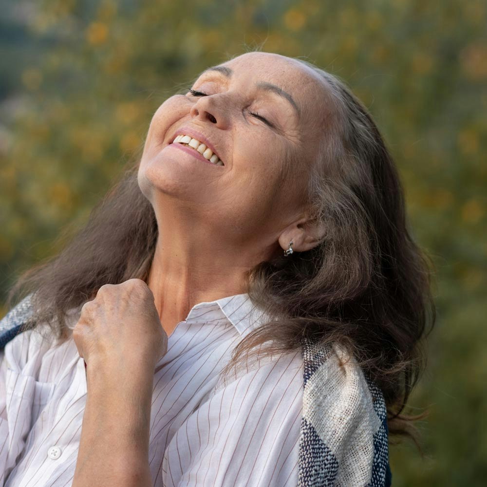 Mature woman closing eyes and smiling with blepharoplasty procedure outdoors