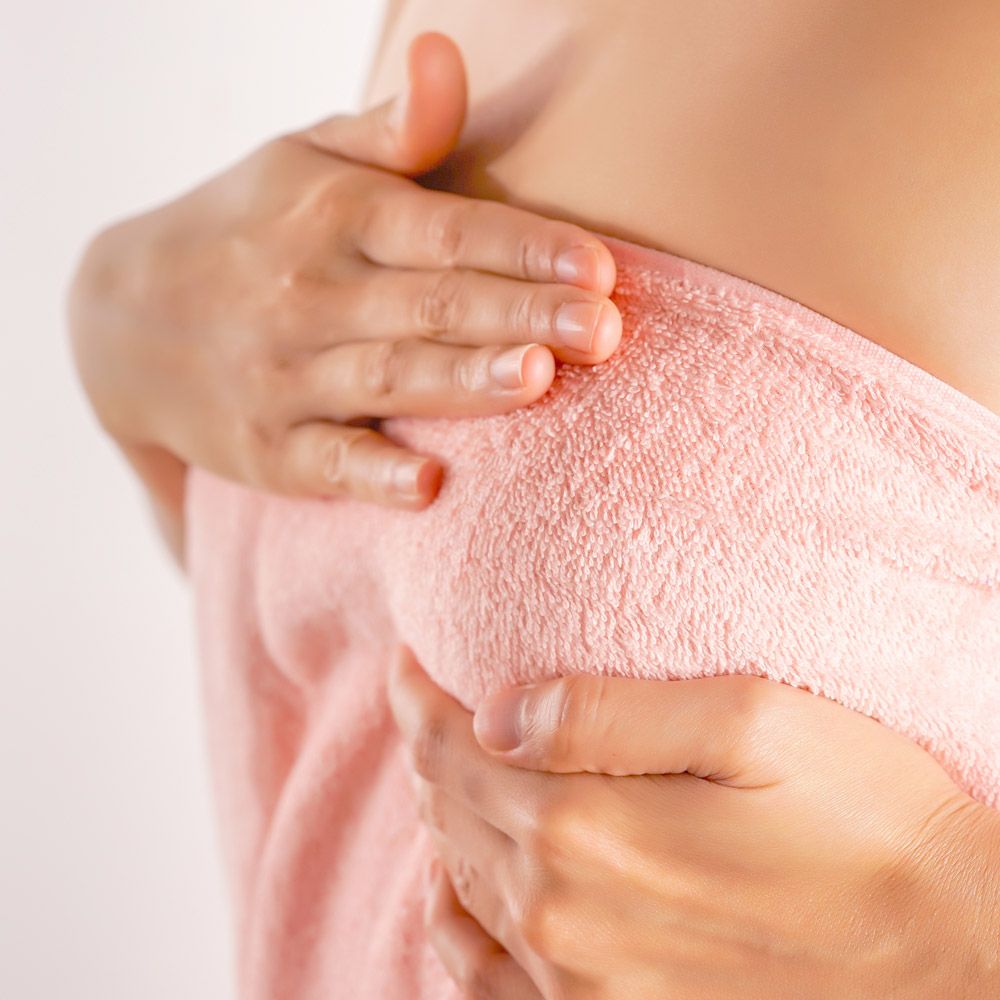 Woman holding towel over breast