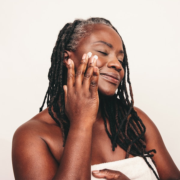Mature woman moisturizing face after facelift