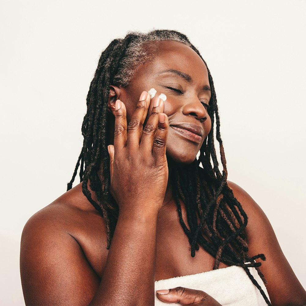 Mature woman moisturizing face after facelift