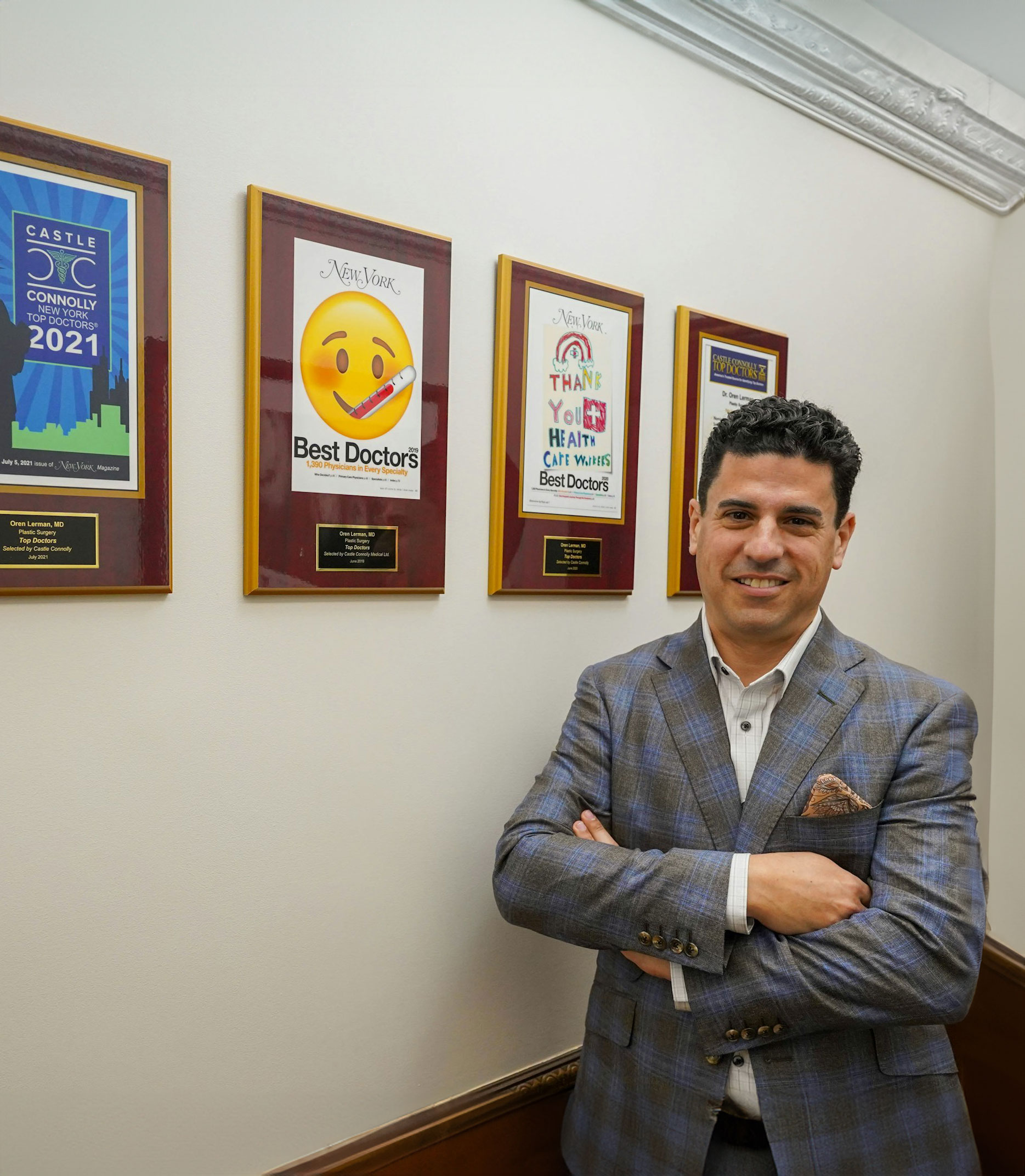 Dr. Oren Lerman standing in office hallway beside framed Top Doctors awards