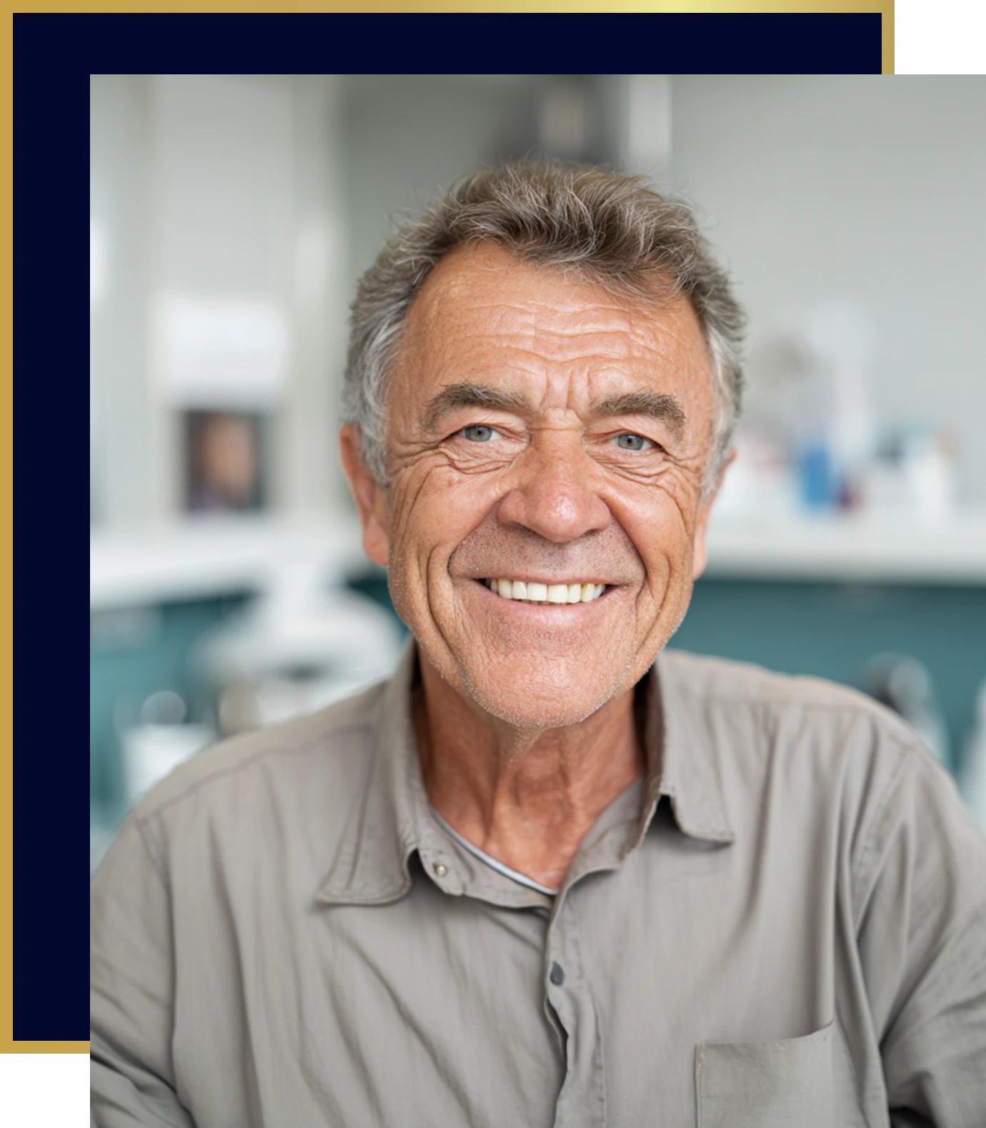 Smiling older man with gray hair wearing a light button-down shirt, seated in a dental office with exam equipment softly blurred in the background.