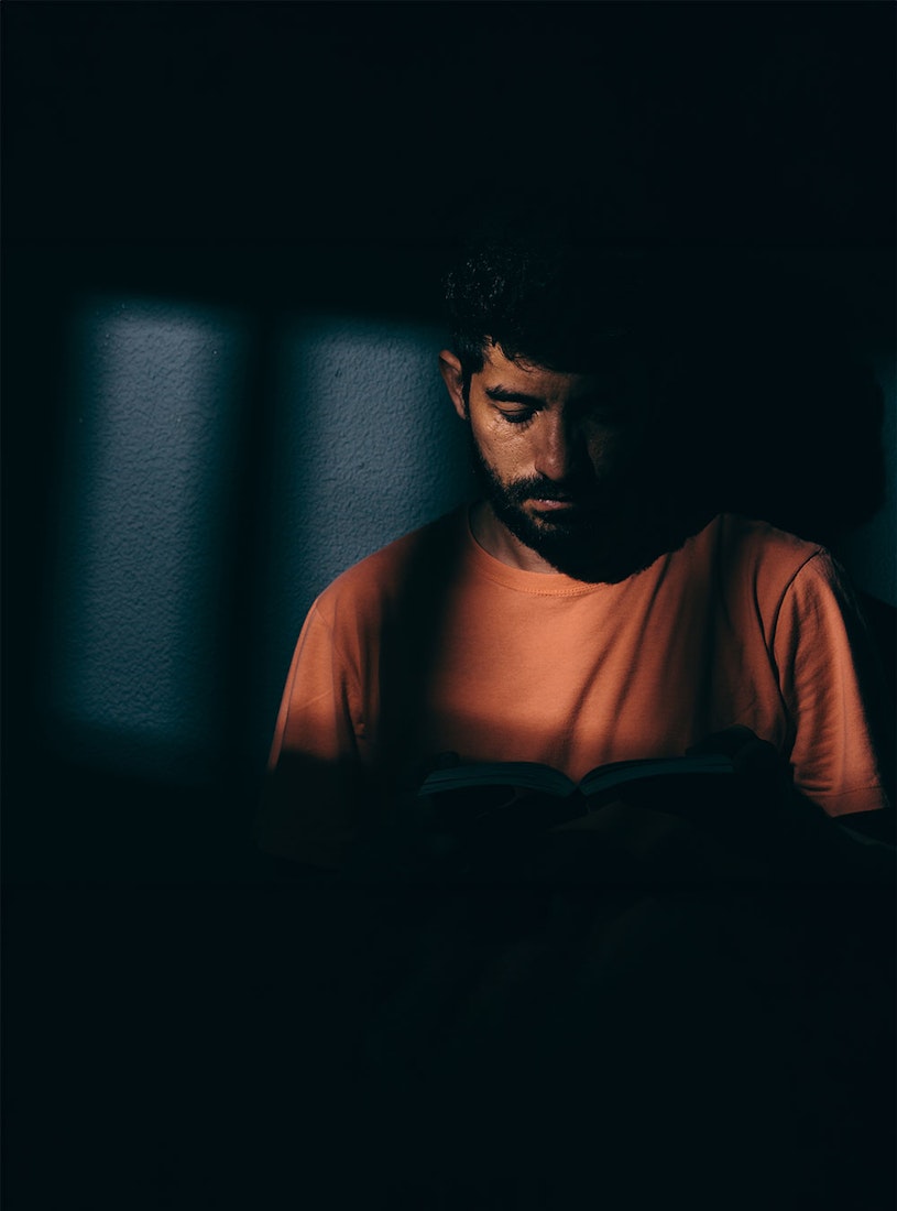 Man reading in a dark jail cell