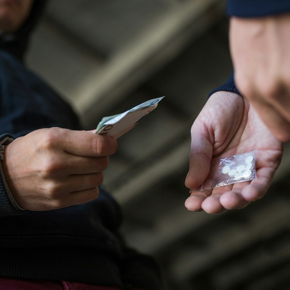 people exchanging pills for cash in a drug deal