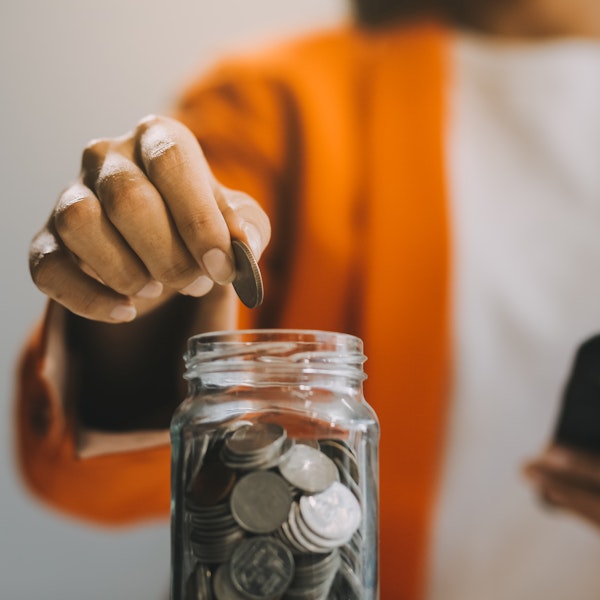 Person adding money to a glass jar