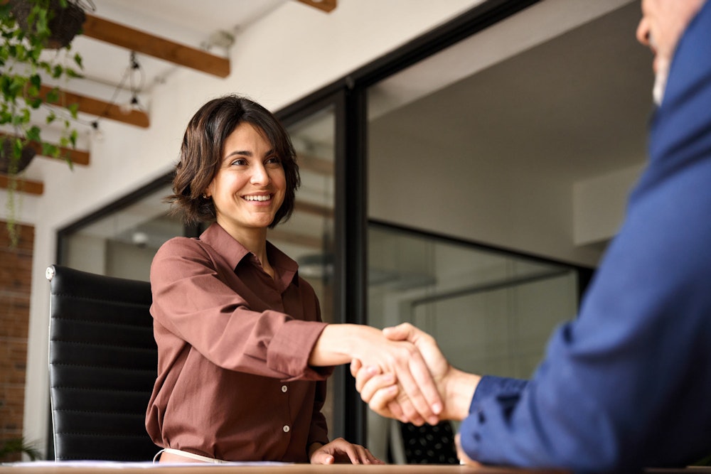 woman shaking hands across table