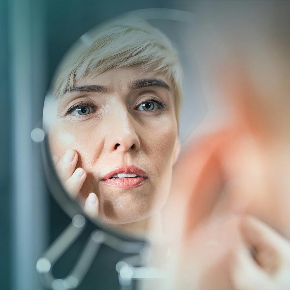woman studying her face in the mirror