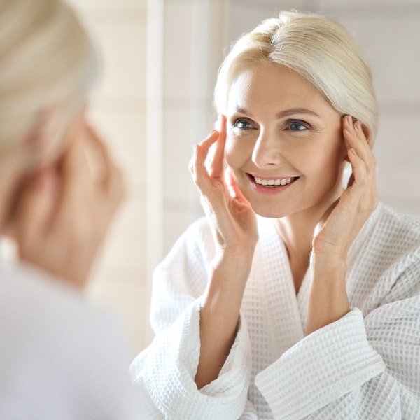 Smiling woman looking in mirror after JUVÉDERM VOLUMA XC treatment