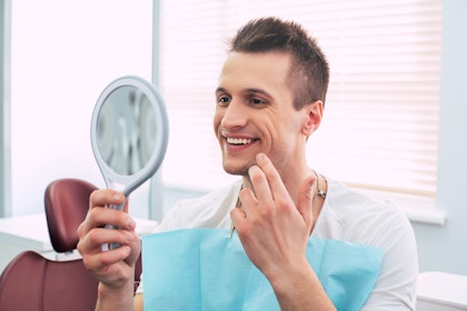 Man smiling into handheld mirror