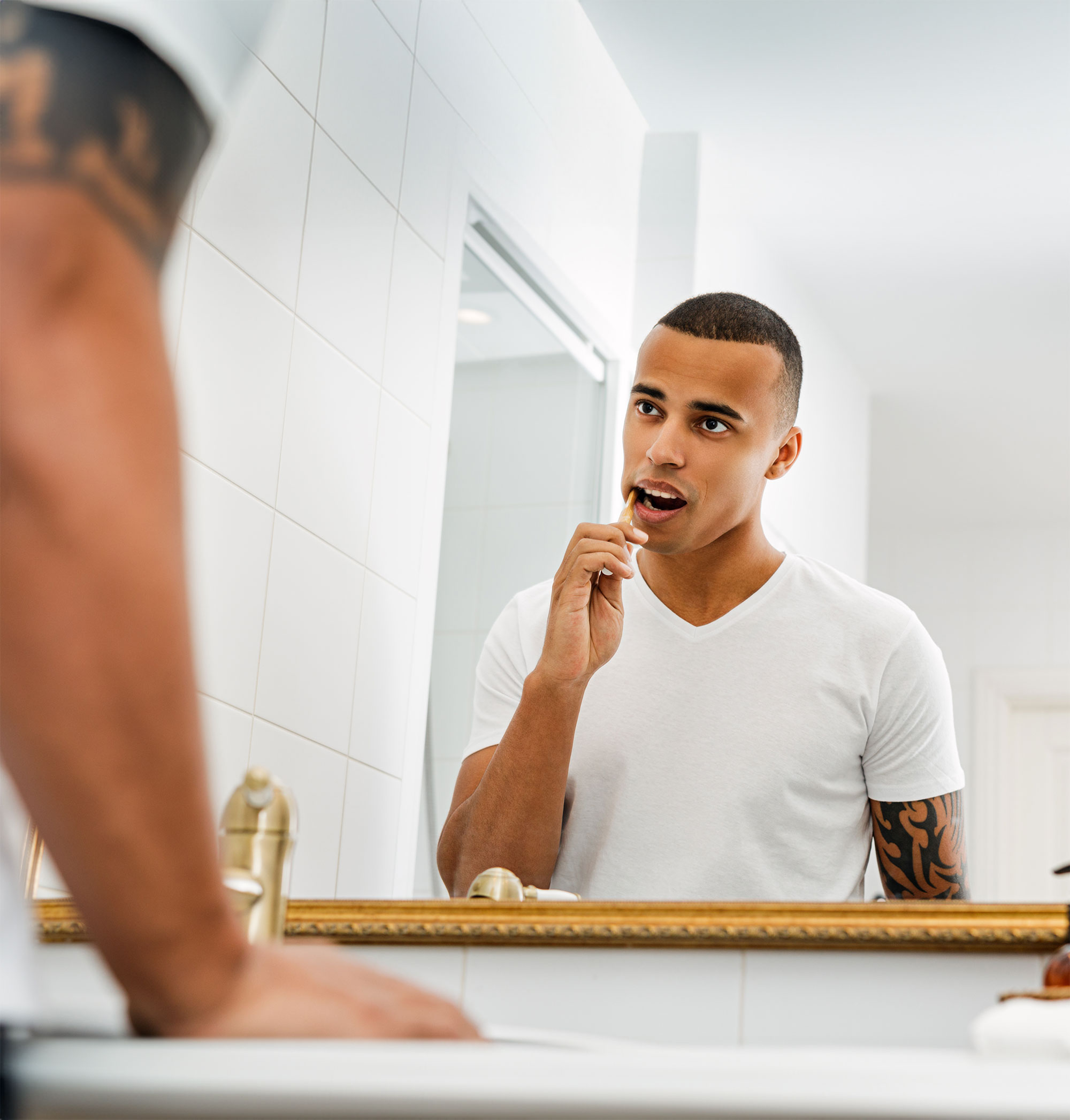 Man looking in the mirror while brushing his teeth