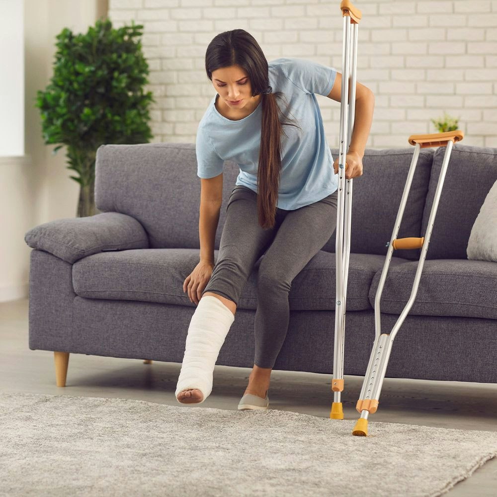Woman with leg in cast easing down onto couch