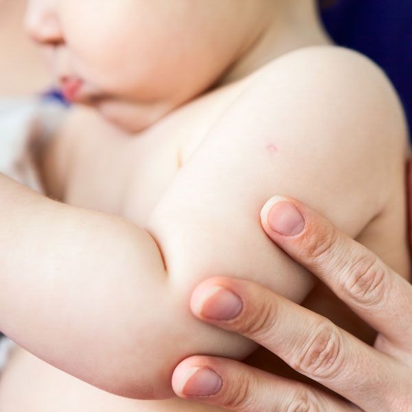 A parent touching their baby's arm and shoulder