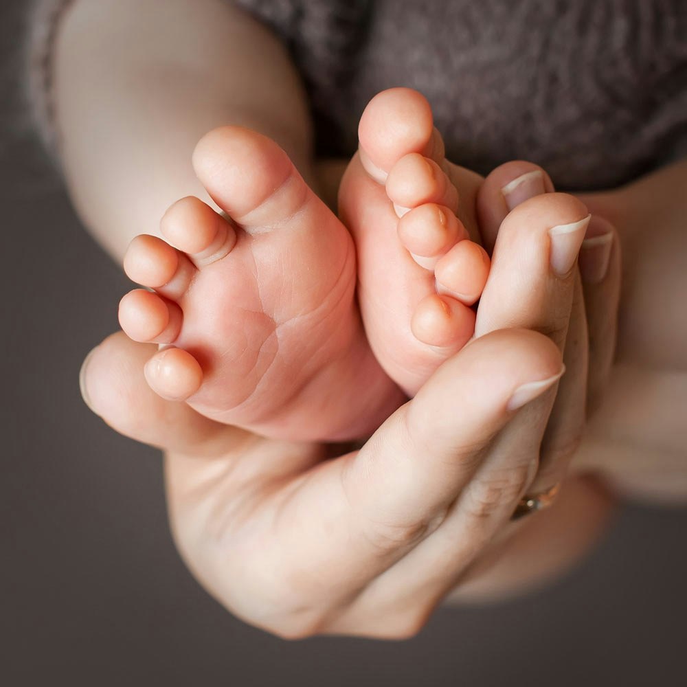 A close-up shot of a baby's feet being held by patient