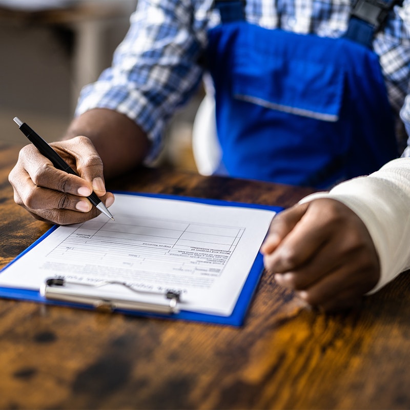 a man with a cast filling out a worker's comp form