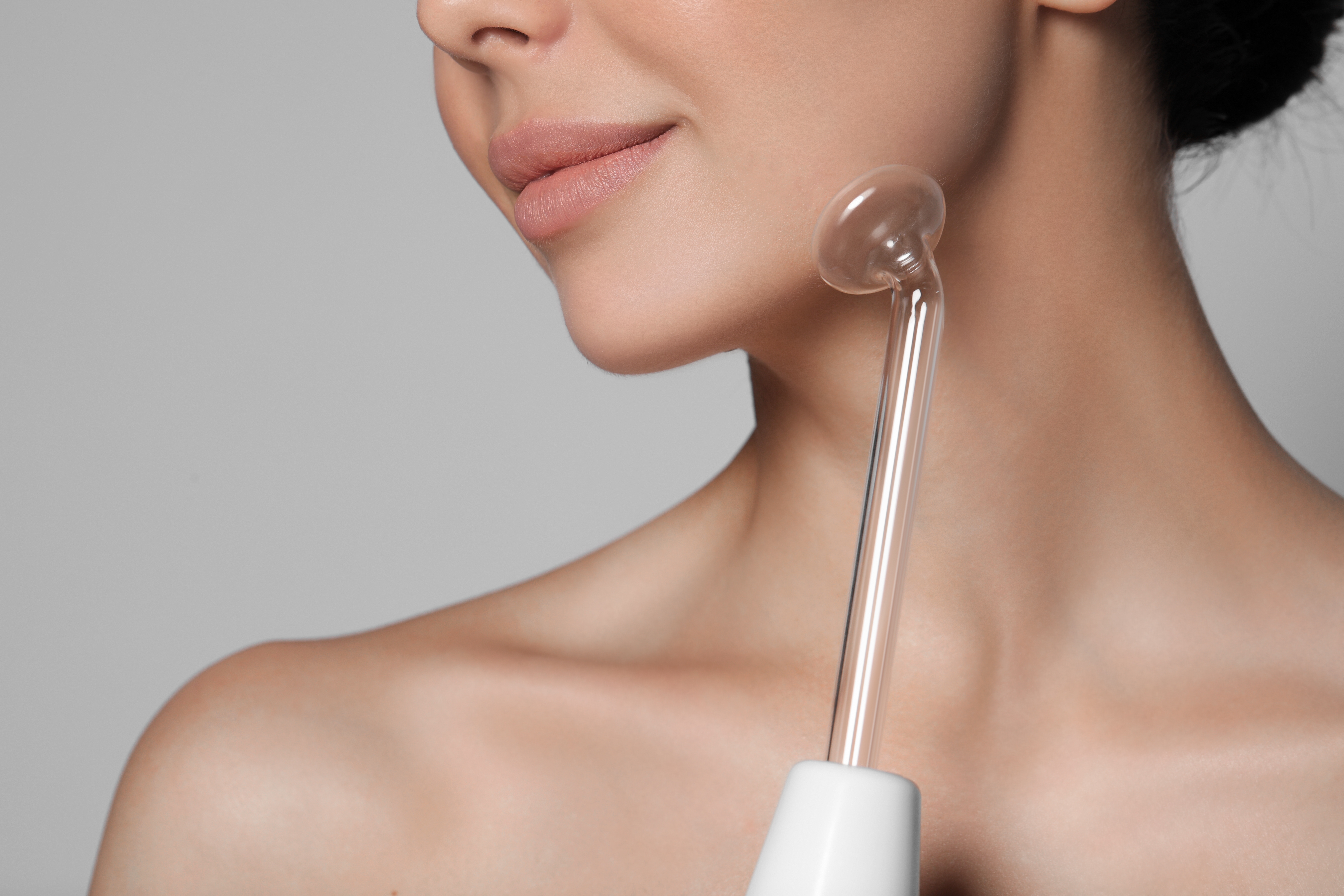 Woman using a high frequency device on jawline