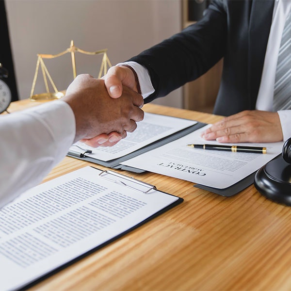 Lawyer sitting at table shaking hands with client