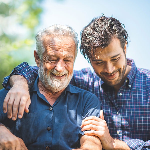 Adult man side hugging senior man