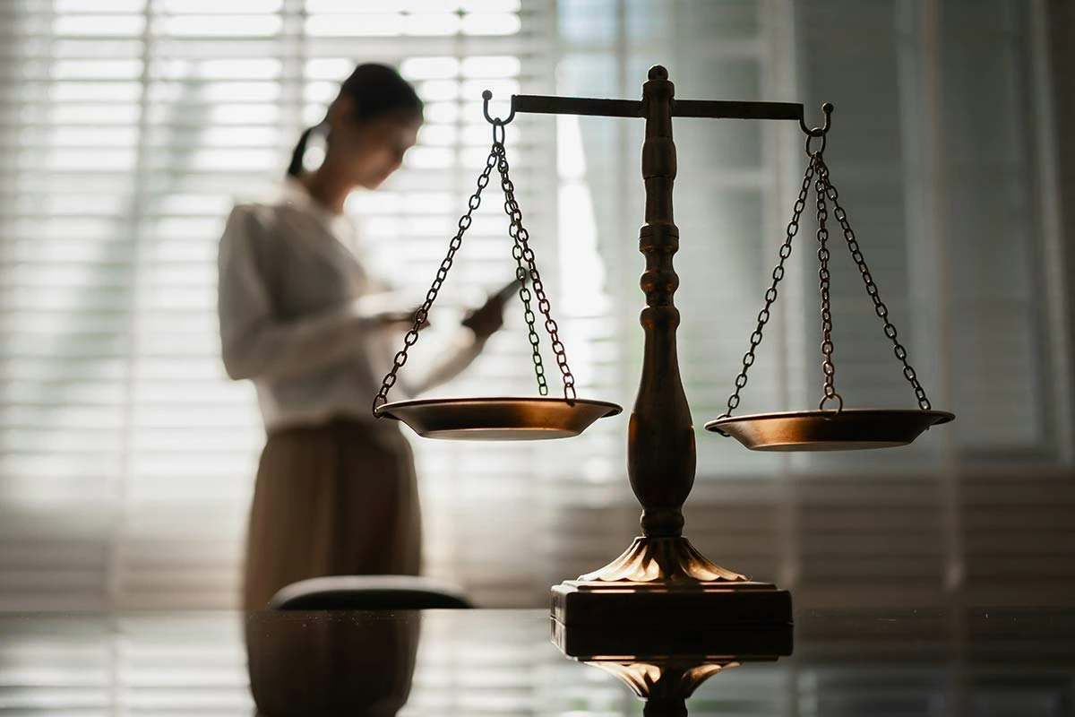justice scales and woman reading in background