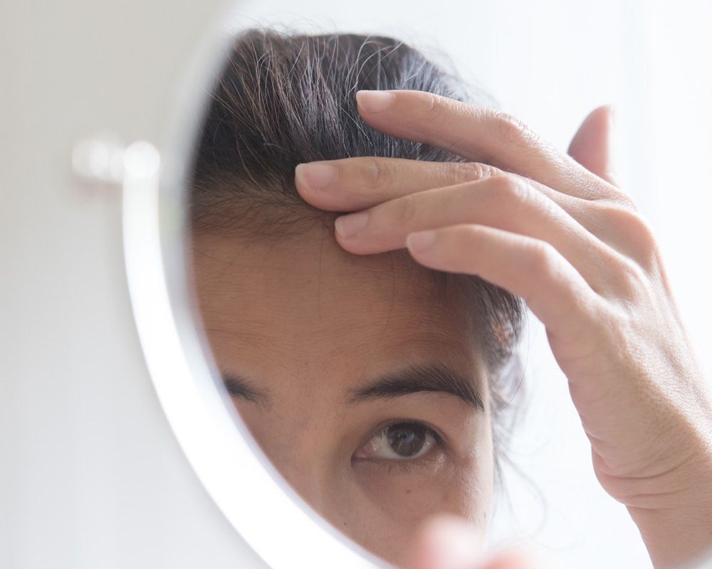 Woman reviewing hairline in mirror