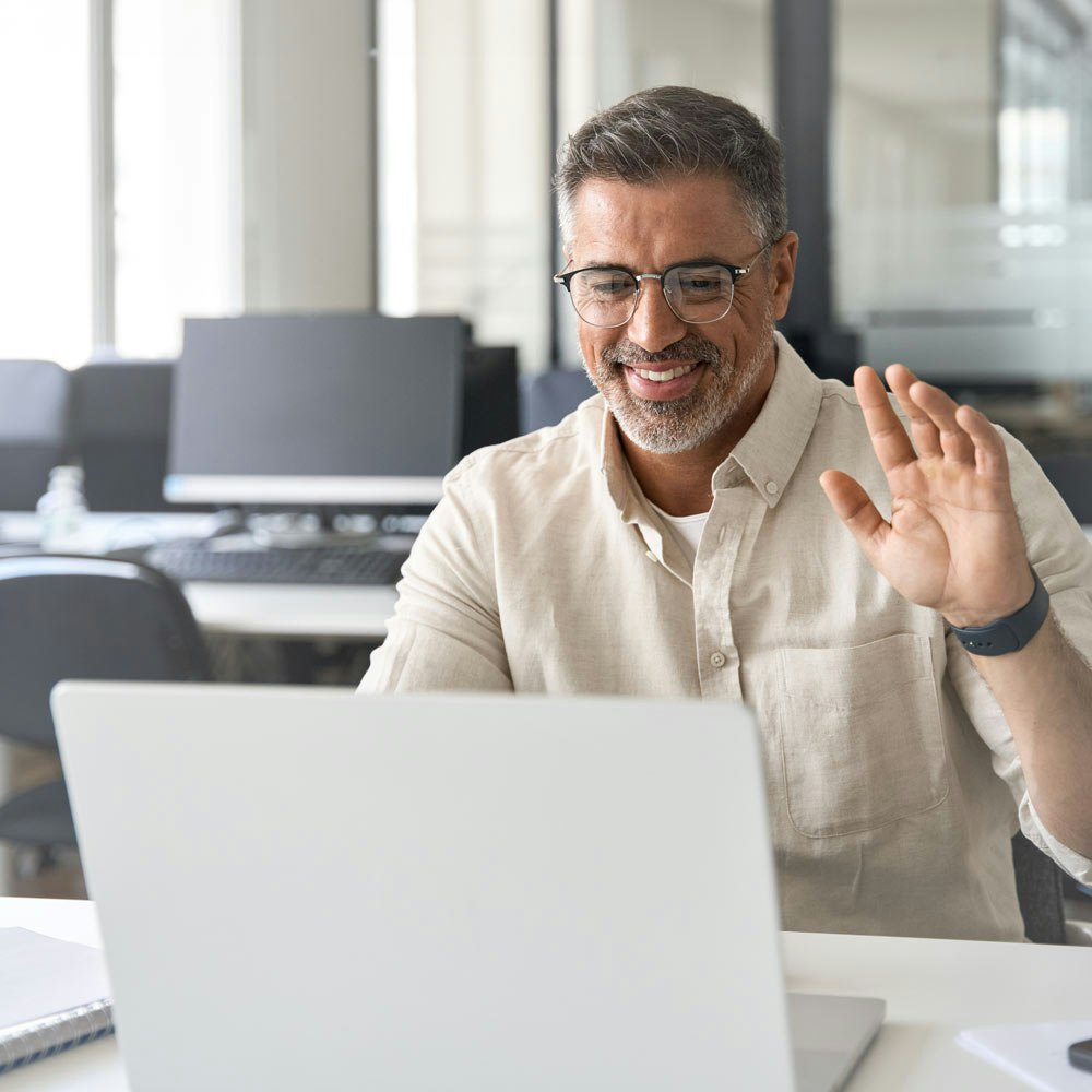 Mature man waving during a virtual consultation
