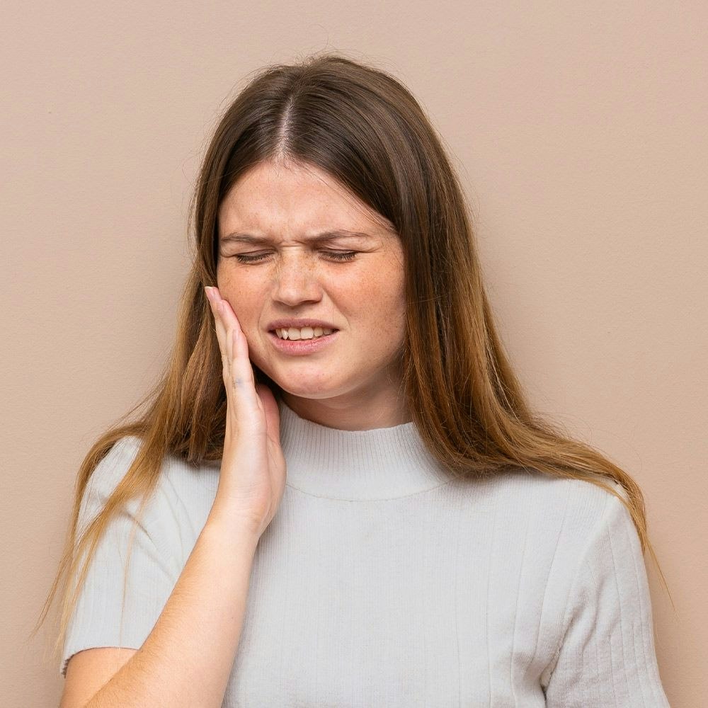 Teenage girl holding jaw in pain