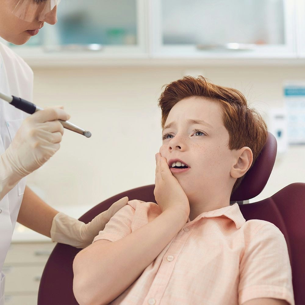 Pediatric dentistry patient holding mouth in pain