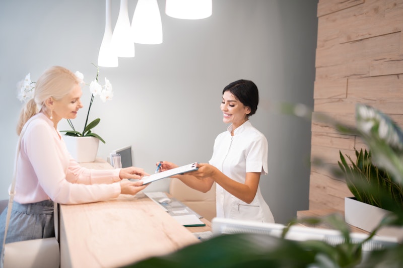 Employee handing patient paperwork