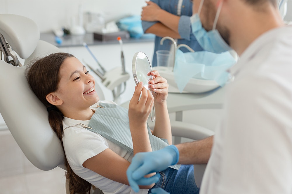 a child at a dentist holding a mirror
