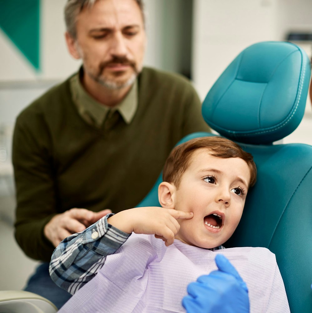 Kid pointing at his mouth at the dentist