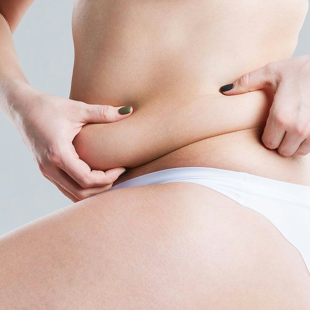 woman grabbing excess fat in her midsection