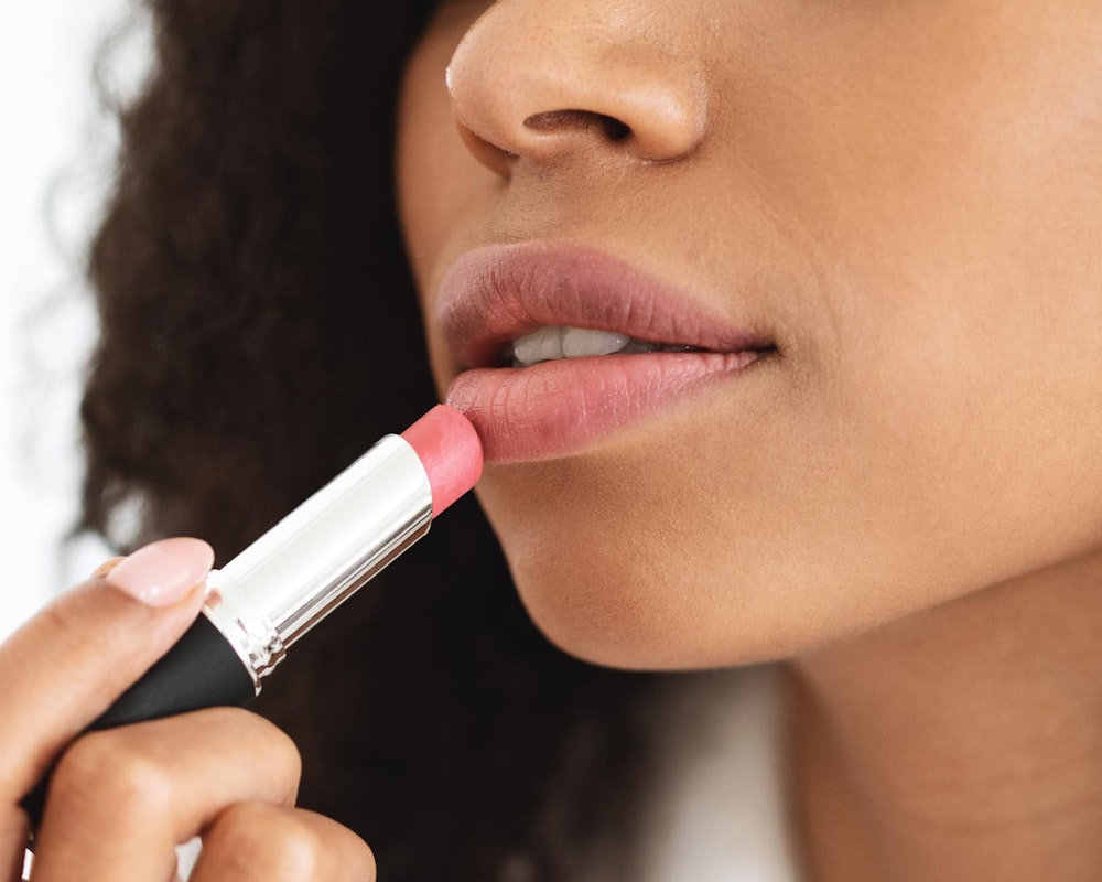 woman with full, beautiful lips applying lipstick