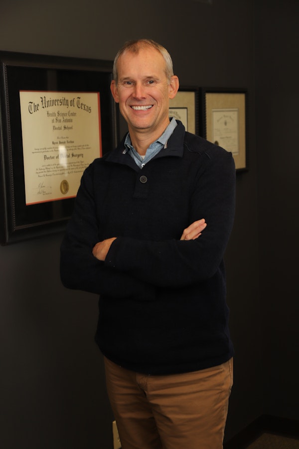 Dr. Byron J. Nordhus standing in front of his dental logo.