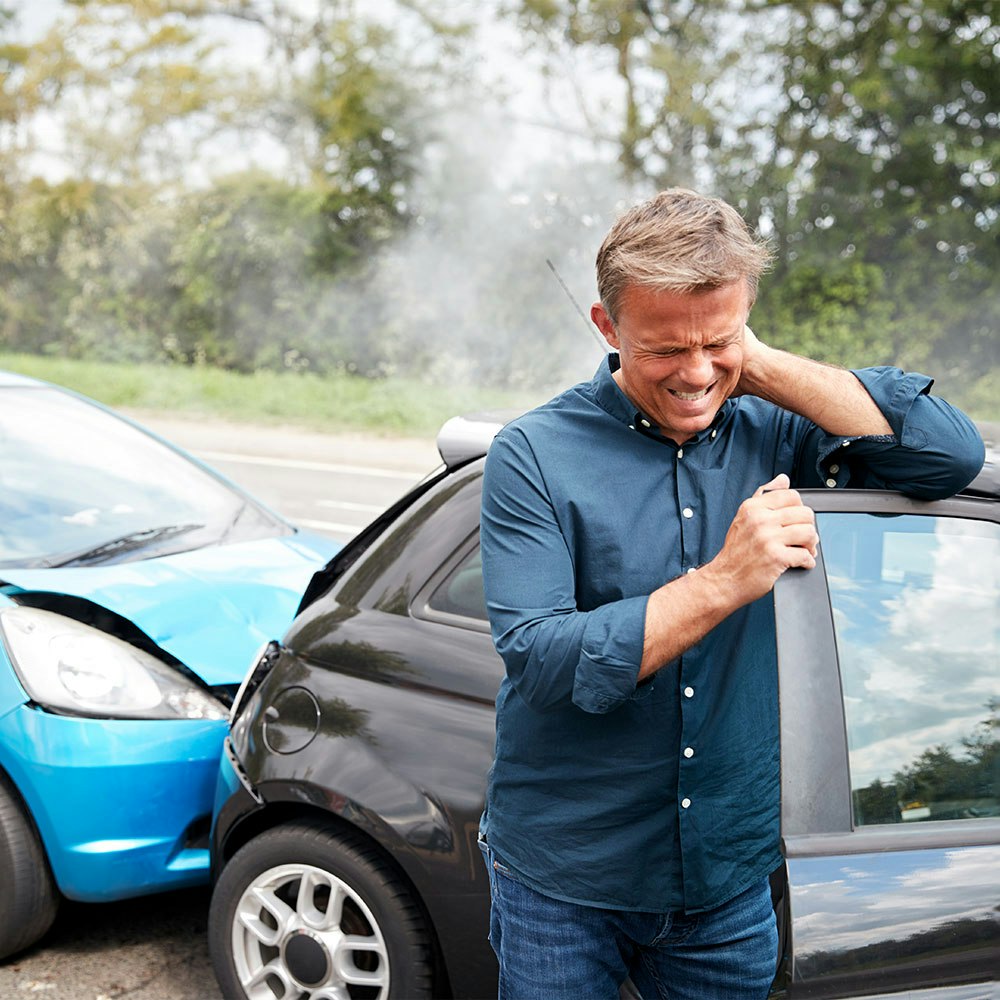 Man rubbing his neck after getting in a car wreck