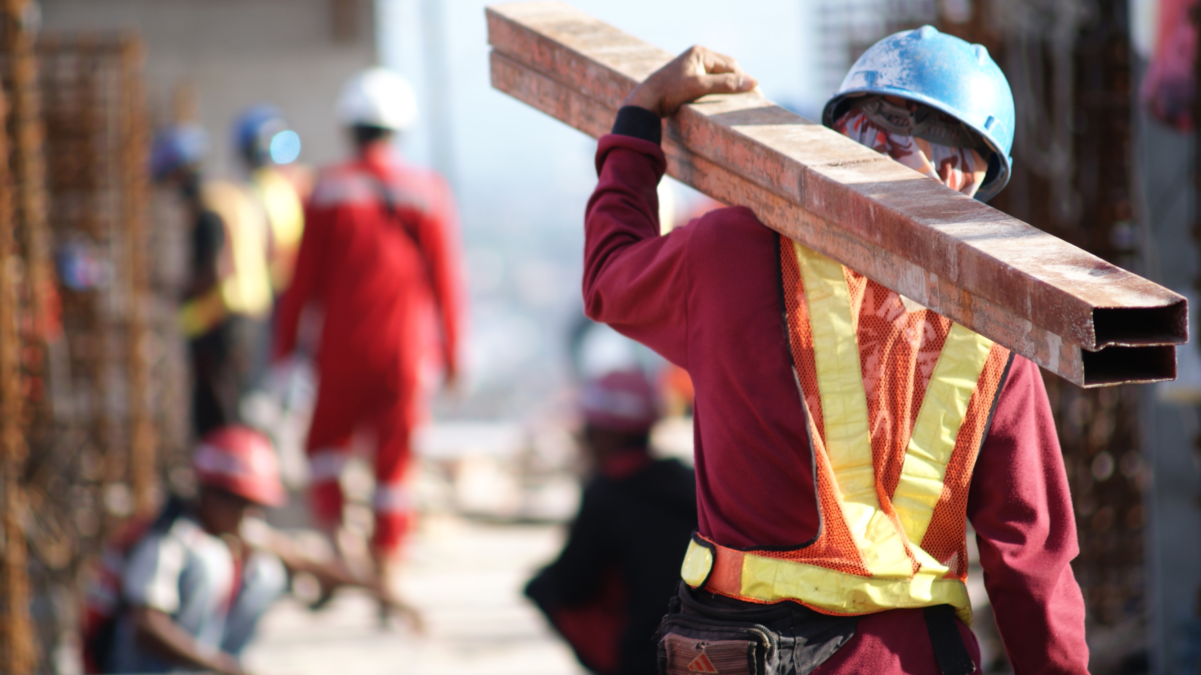 Construction worker carrying beams