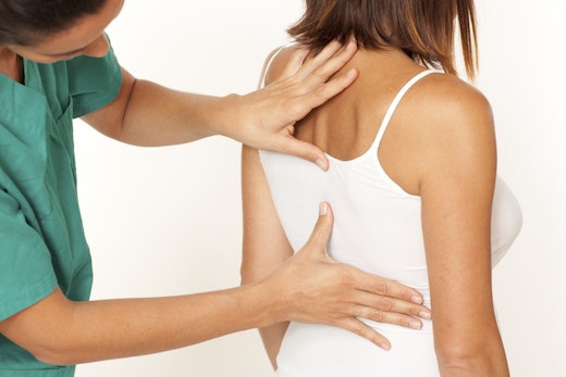 woman getting her back looked at by a doctor