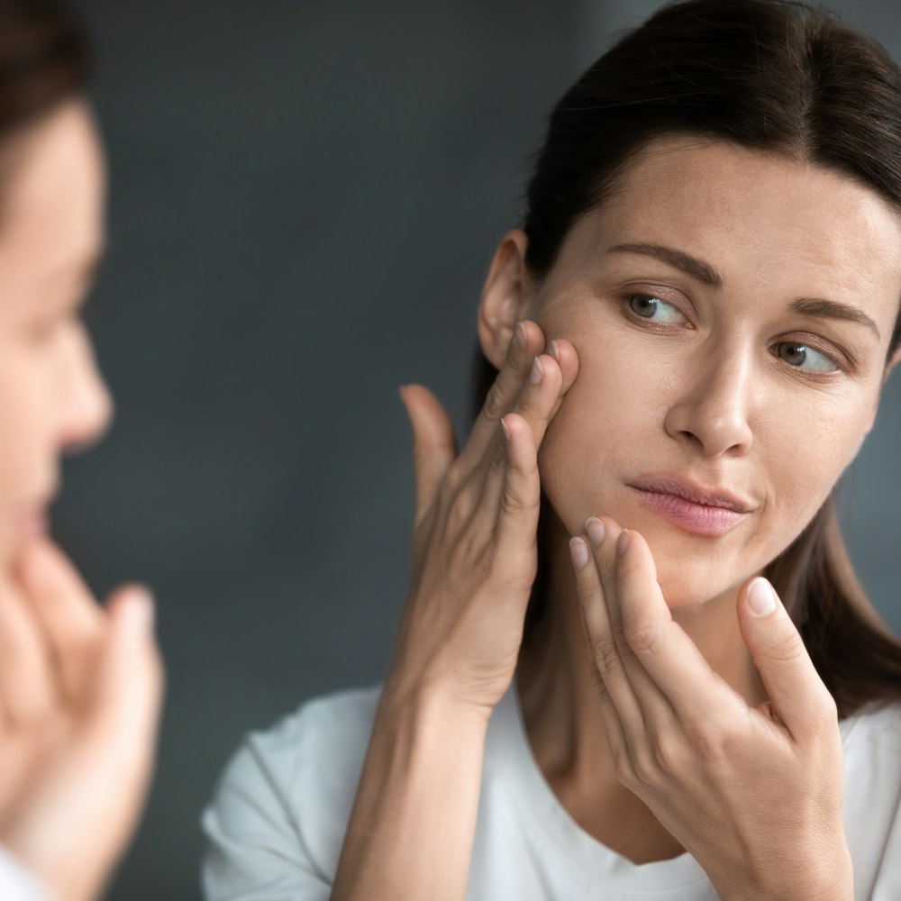 Woman looking at skin in mirror