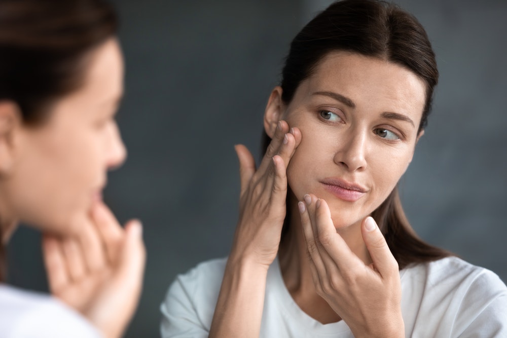 Woman looking at skin in mirror