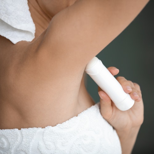 woman using stick of deodorant