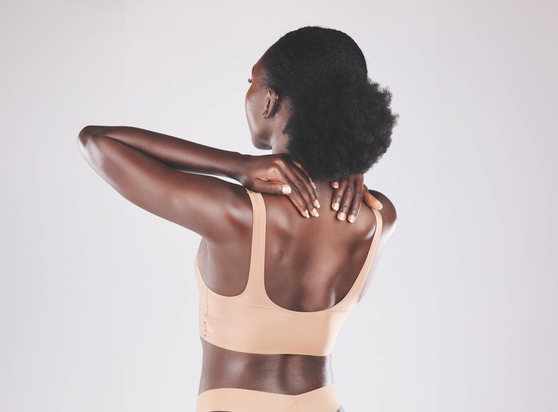 Back of darker-skinned woman touching neck