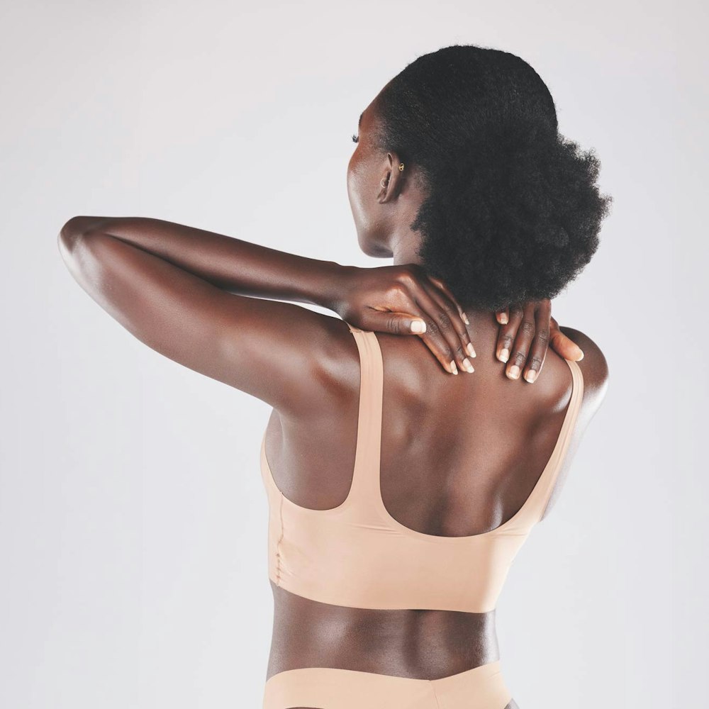 Back of darker-skinned woman touching neck