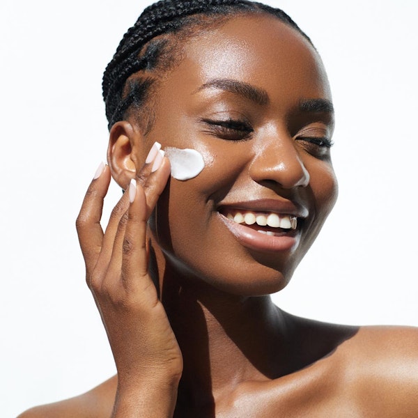 Smiling woman applying sunscreen
