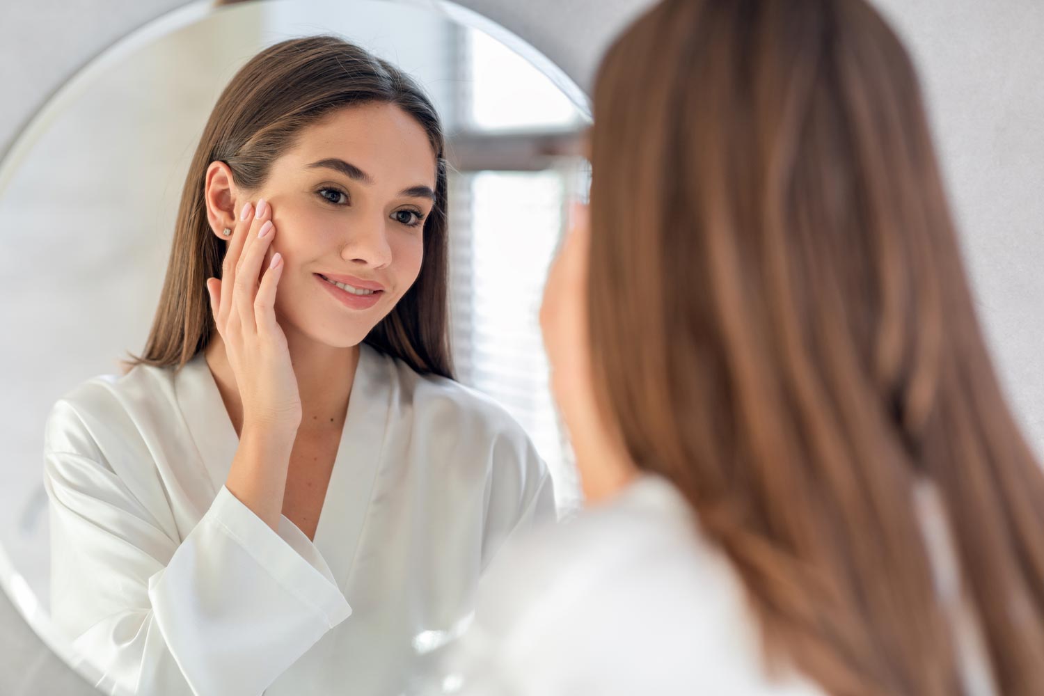 Microneedling client admiring glowing skin in the mirror